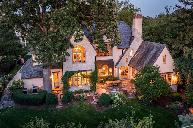 21 Forest Ave, Naperville, IL 60540 - back of house with a chimney, stone siding, a patio, stucco siding, and a lawn