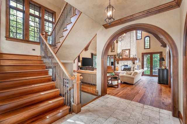 21 Forest Ave, Naperville, IL 60540 - stairway with stone tile floors, a high ceiling, a chandelier, arched walkways, and crown molding