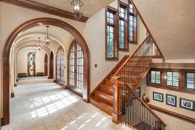 21 Forest Ave, Naperville, IL 60540 - stairway featuring arched walkways, a chandelier, stone tile flooring, french doors, and a towering ceiling