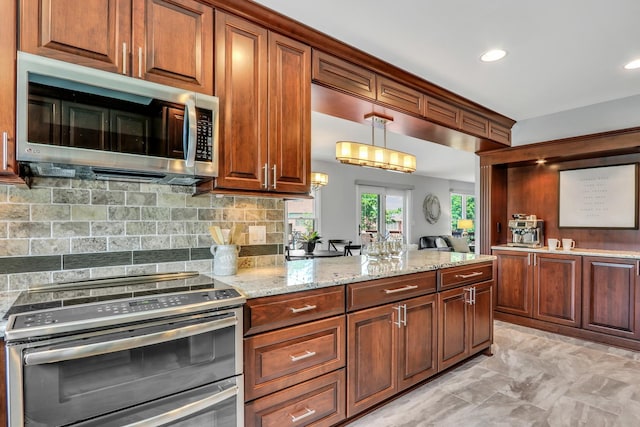 347 Yorkshire Dr, Mundelein, IL 60060 - kitchen featuring stainless steel appliances, backsplash, light stone counters, hanging light fixtures, and light marble finish floors
