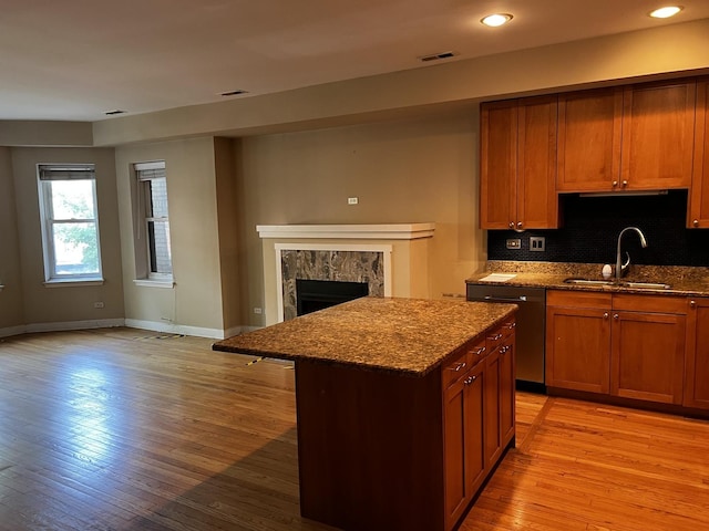 7513 N Winchester Ave Unit 1, Chicago, IL 60626 - kitchen with a sink, dark stone counters, baseboards, a center island, and light wood-style flooring