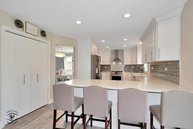 8456 Meadows Edge Trl, Tinley Park, IL 60487 - kitchen featuring wall chimney exhaust hood, appliances with stainless steel finishes, light countertops, light wood-type flooring, and decorative backsplash