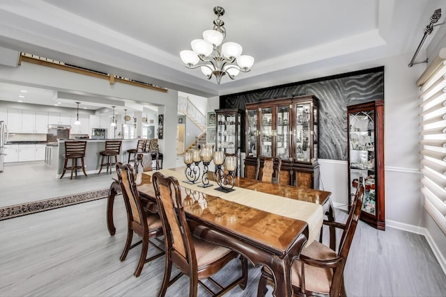 27117 Ashgate Xing, Plainfield, IL 60585 - dining space with a tray ceiling, a chandelier, light wood-type flooring, and stairs