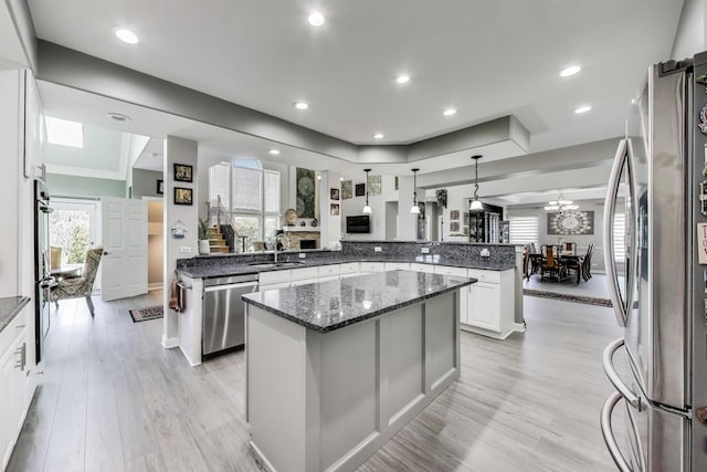 27117 Ashgate Xing, Plainfield, IL 60585 - kitchen with appliances with stainless steel finishes, a kitchen island, light wood-style flooring, dark stone counters, and a peninsula