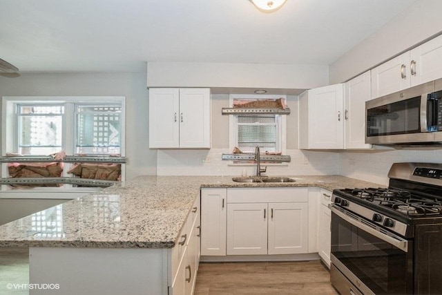 3411 W 59th St, Chicago, IL 60629 - kitchen with appliances with stainless steel finishes, a sink, white cabinetry, a peninsula, and light wood-style floors