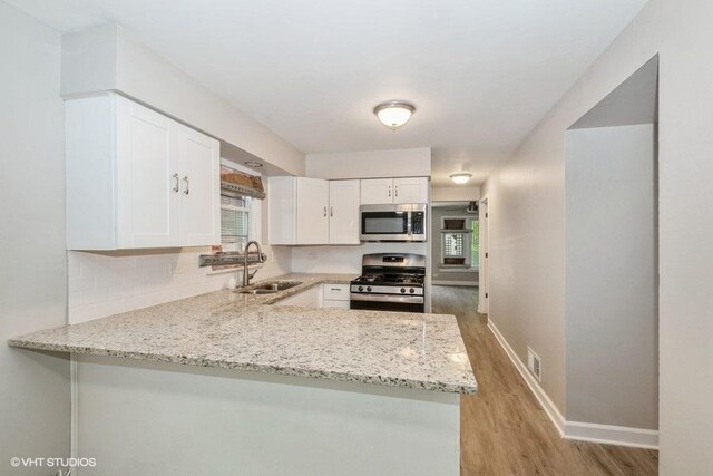 3411 W 59th St, Chicago, IL 60629 - kitchen with appliances with stainless steel finishes, a sink, light wood-style flooring, white cabinets, and baseboards