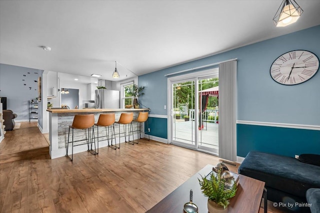 688 Regent Dr, Crystal Lake, IL 60014 - kitchen with freestanding refrigerator, wood finished floors, a breakfast bar area, and hanging light fixtures