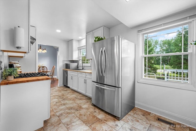 688 Regent Dr, Crystal Lake, IL 60014 - kitchen with stainless steel appliances, butcher block counters, white cabinets, plenty of natural light, and recessed lighting