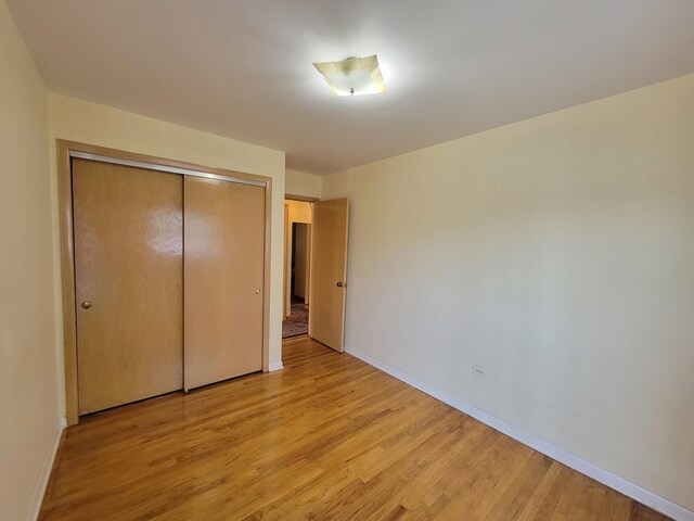 3023 Paris Ave Unit 207, River Grove, IL 60171 - unfurnished bedroom with light wood finished floors, baseboards, and a closet