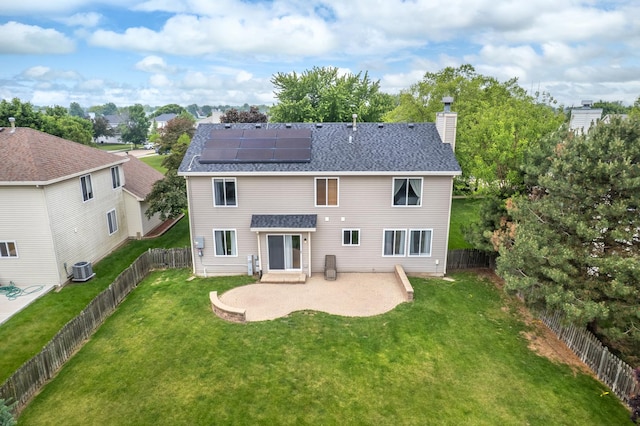 2278 Andrew Trl, Montgomery, IL 60538 - back of property featuring a patio area, a chimney, roof mounted solar panels, roof with shingles, and a fenced backyard