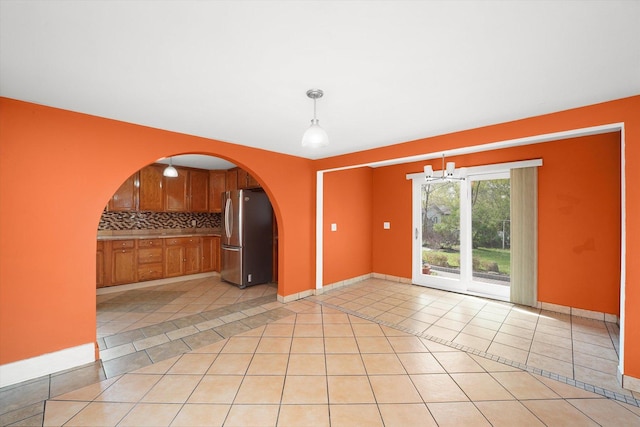 2203 Gilead Ave, Zion, IL 60099 - kitchen featuring freestanding refrigerator, light tile patterned flooring, decorative backsplash, and arched walkways