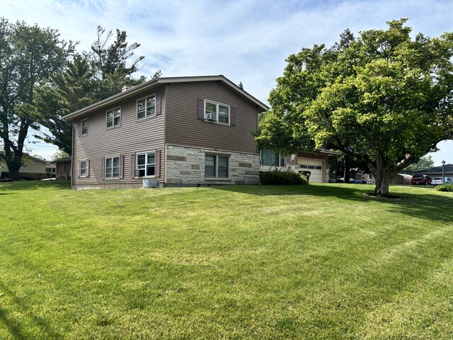 205 Beacon Dr, Belvidere, IL 61008 - rear view of house with stone siding, a lawn, and an attached garage