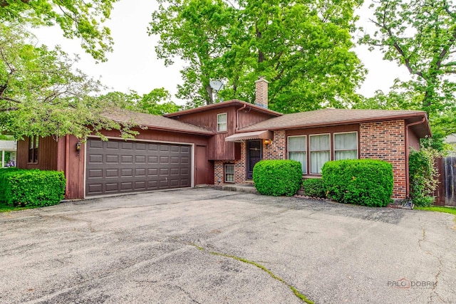 1417 N Mcaree Rd, Waukegan, IL 60085 - tri-level home with an attached garage, a chimney, driveway, and brick siding