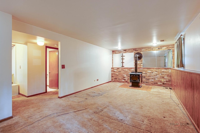 1417 N Mcaree Rd, Waukegan, IL 60085 - unfurnished living room with carpet flooring, a wood stove, baseboards, and brick wall