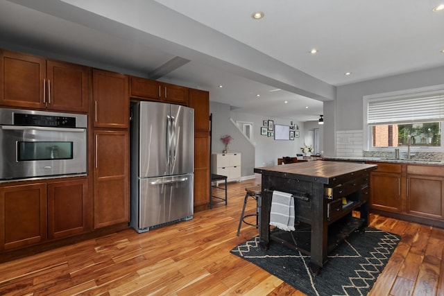 592 E 13th St, Lockport, IL 60441 - kitchen featuring appliances with stainless steel finishes, light wood-type flooring, decorative backsplash, recessed lighting, and brown cabinets