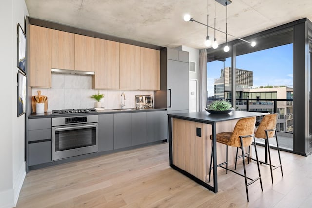 234 W Polk St Unit 3209, Chicago, IL 60607 - kitchen with oven, dark countertops, a sink, a breakfast bar, and decorative backsplash