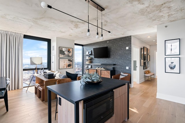 234 W Polk St Unit 3209, Chicago, IL 60607 - kitchen featuring black microwave, light wood finished floors, dark countertops, expansive windows, and a kitchen breakfast bar