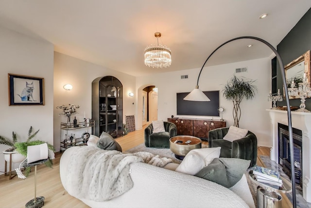 606 W Aldine Ave Unit 3E, Chicago, IL 60657 - living area featuring arched walkways, wood finished floors, a chandelier, and a glass covered fireplace