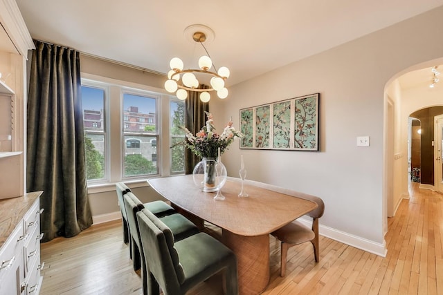 606 W Aldine Ave Unit 3E, Chicago, IL 60657 - dining room featuring arched walkways, a chandelier, and light wood finished floors
