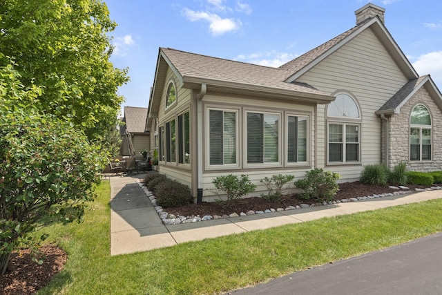 1908 Timbers Edge Cir, Joliet, IL 60431 - view of home's exterior featuring a shingled roof, a chimney, stone siding, and a patio area