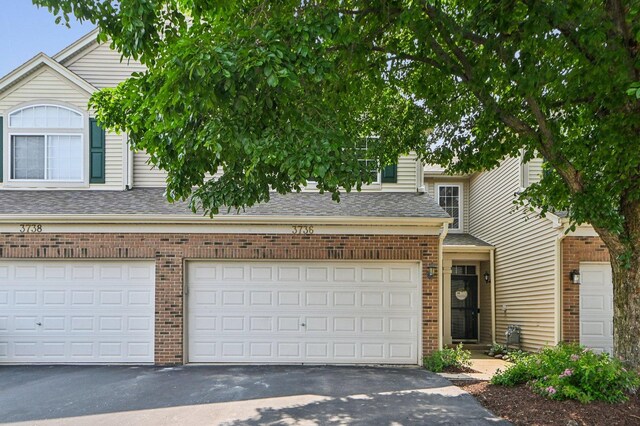 3736 Munson St, Plano, IL 60545 - view of front facade with asphalt driveway, brick siding, a shingled roof, and a garage