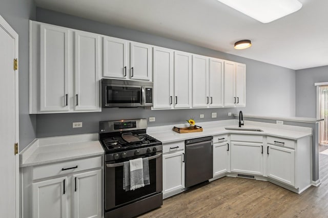 3736 Munson St, Plano, IL 60545 - kitchen with stainless steel appliances, a peninsula, light wood finished floors, and white cabinets