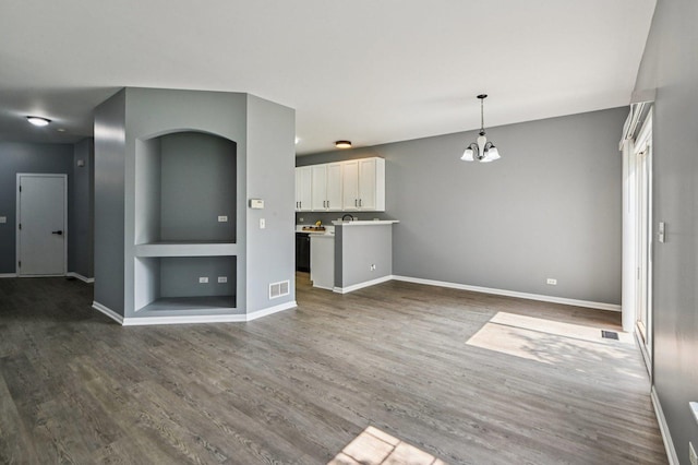 3736 Munson St, Plano, IL 60545 - unfurnished living room featuring dark wood-style flooring, a chandelier, and built in shelves
