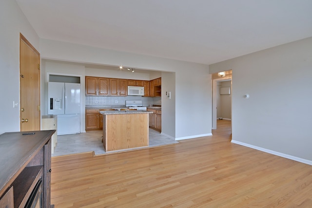 7321 W Fullerton Ave Unit 10, Elmwood Park, IL 60707 - kitchen featuring white appliances, a center island, light wood-style floors, decorative backsplash, and brown cabinetry