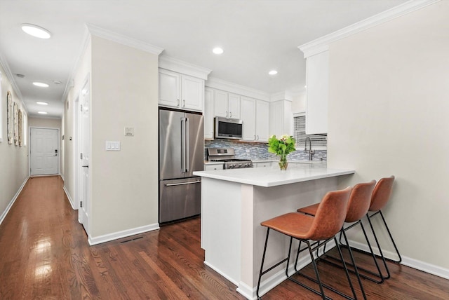 3353 N Kenmore Ave Unit 1, Chicago, IL 60657 - kitchen with stainless steel appliances, a breakfast bar, decorative backsplash, a peninsula, and white cabinets