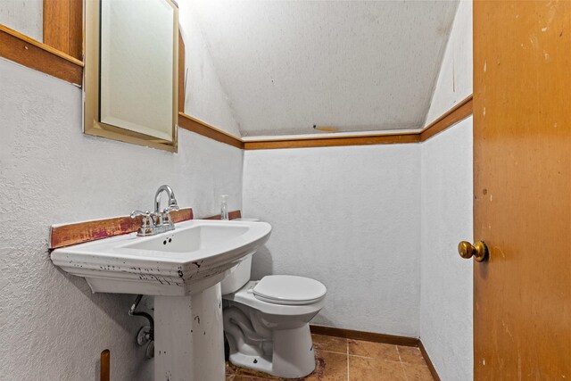 2611 Ellen St, Rockford, IL 61101 - half bathroom featuring a textured wall, toilet, vaulted ceiling, and baseboards