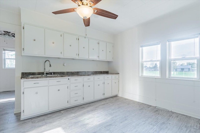800 E Webster St, Clinton, IL 61727 - kitchen with a sink, white cabinets, a ceiling fan, baseboards, and dark stone countertops