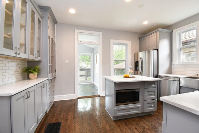 1234 Edmer Ave, Oak Park, IL 60302 - kitchen featuring gray cabinets, appliances with stainless steel finishes, tasteful backsplash, glass insert cabinets, and dark wood-type flooring