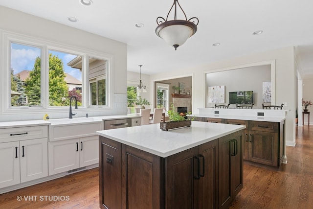 76 Landon Cir, Wheaton, IL 60189 - kitchen with dishwasher, a lit fireplace, dark wood-style flooring, a center island, and white cabinets