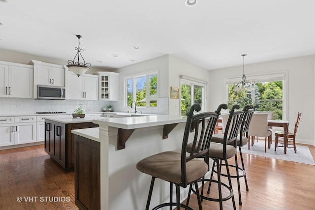 76 Landon Cir, Wheaton, IL 60189 - kitchen featuring stainless steel microwave, a kitchen island, dark wood-style floors, light countertops, and tasteful backsplash