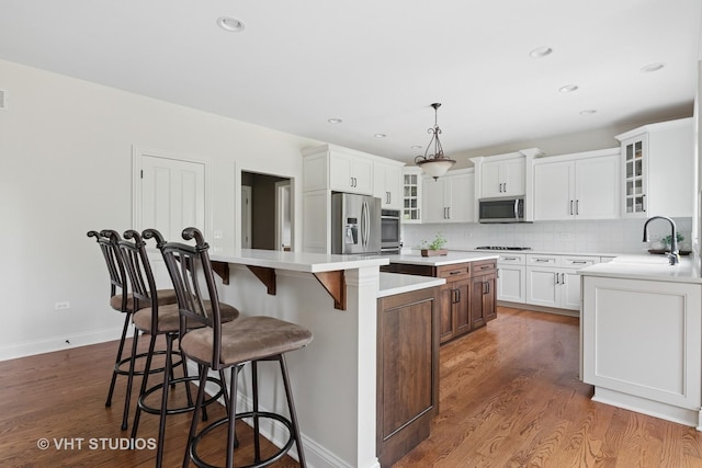 76 Landon Cir, Wheaton, IL 60189 - kitchen featuring a kitchen island, stainless steel appliances, dark wood-style flooring, backsplash, and a breakfast bar area