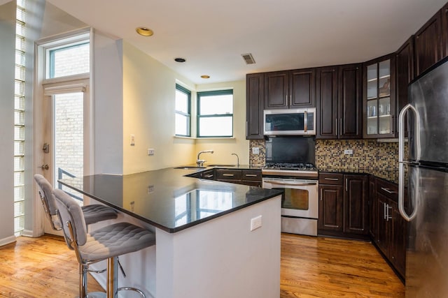 2943 N Lincoln Ave Unit 201, Chicago, IL 60657 - kitchen with appliances with stainless steel finishes, a sink, a breakfast bar, light wood-type flooring, and recessed lighting