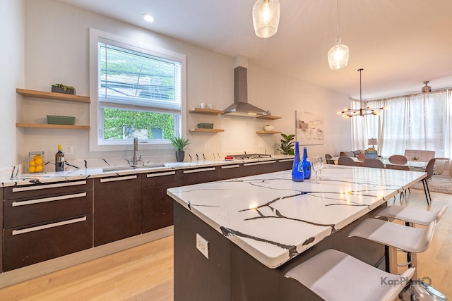 2414 W Grenshaw St Unit 1E, Chicago, IL 60612 - kitchen with ventilation hood, open shelves, light wood finished floors, a breakfast bar, and decorative light fixtures