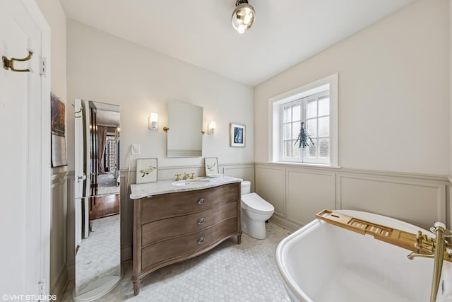 1141 N Ridgeland Ave, Oak Park, IL 60302 - bathroom with a freestanding tub, vanity, wainscoting, toilet, and a decorative wall