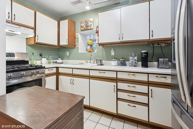 1140 W Barry Ave, Chicago, IL 60657 - kitchen with appliances with stainless steel finishes, under cabinet range hood, white cabinets, light countertops, and light tile patterned floors