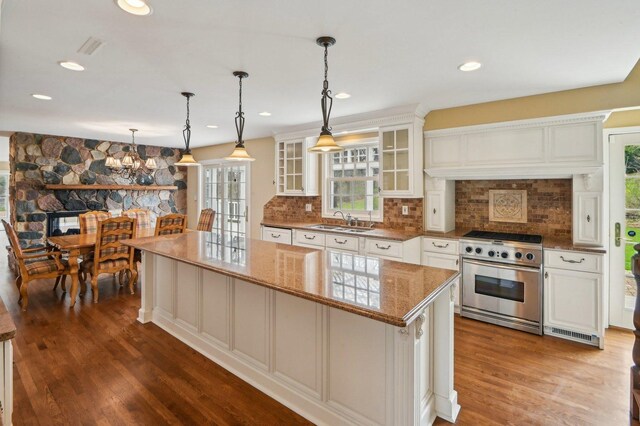 21956 N Hickory Hill Dr, Kildeer, IL 60047 - kitchen with stainless steel range with gas cooktop, a sink, a center island, light stone counters, and glass insert cabinets