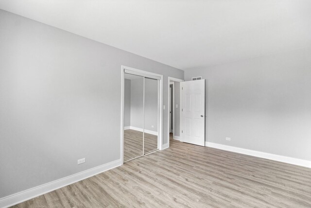15240 Woodlawn Ave, Dolton, IL 60419 - unfurnished bedroom with light wood-style flooring, baseboards, and a closet
