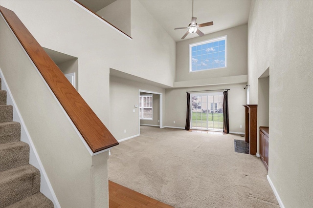 2303 Blanche Ln Unit B, Champaign, IL 61822 - unfurnished living room featuring a towering ceiling, stairs, ceiling fan, and light colored carpet