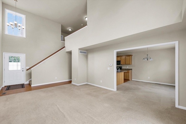 2303 Blanche Ln Unit B, Champaign, IL 61822 - unfurnished living room with a chandelier, light colored carpet, a high ceiling, and stairway
