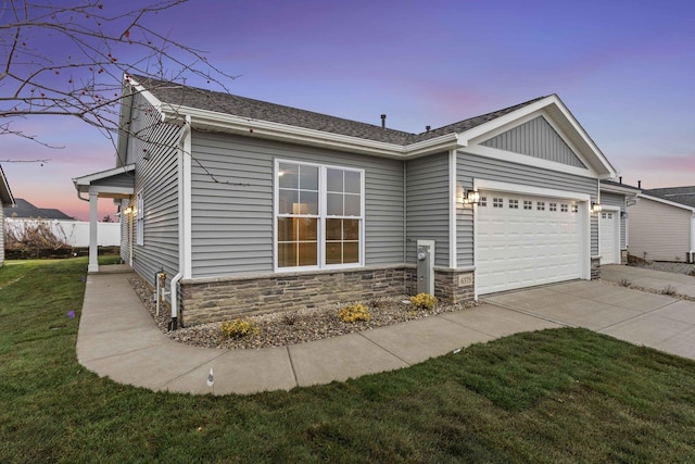 6375 Jasmine Ave, Portage, IN 46368 - view of front facade with concrete driveway, stone siding, a garage, a lawn, and roof with shingles
