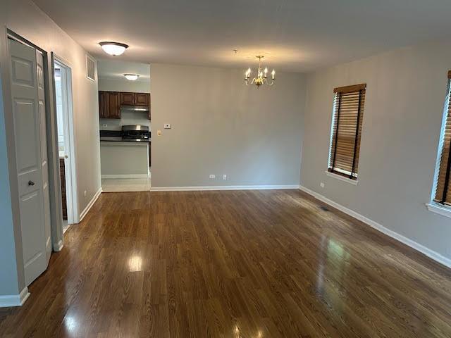 1127 Orleans Dr, Mundelein, IL 60060 - unfurnished living room with dark wood-type flooring, a chandelier, and baseboards