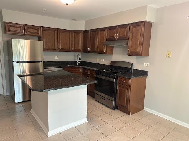 1127 Orleans Dr, Mundelein, IL 60060 - kitchen with appliances with stainless steel finishes, under cabinet range hood, a sink, light tile patterned floors, and a kitchen island