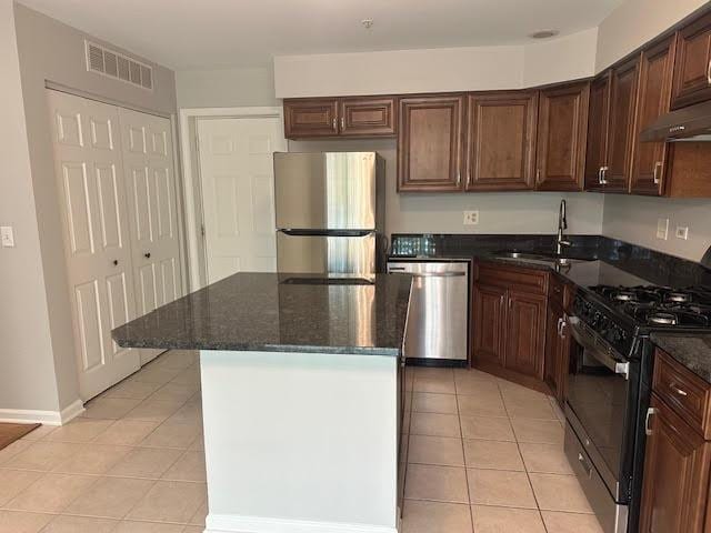 1127 Orleans Dr, Mundelein, IL 60060 - kitchen with appliances with stainless steel finishes, a sink, light tile patterned floors, a center island, and dark stone countertops
