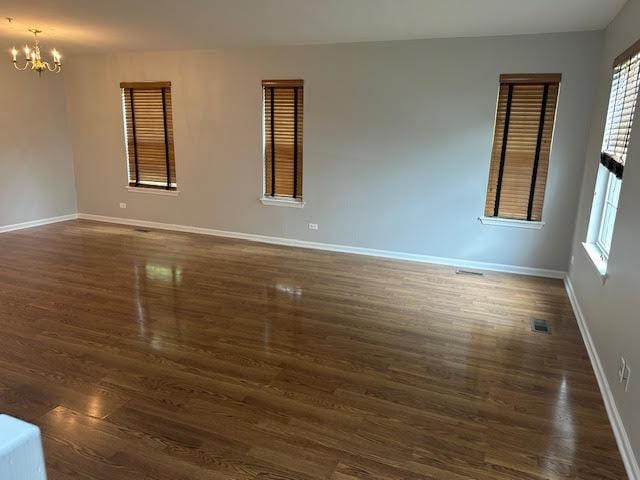 1127 Orleans Dr, Mundelein, IL 60060 - spare room with a chandelier, healthy amount of natural light, dark wood-style flooring, and baseboards