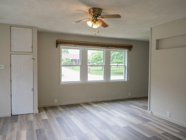 510 W Harrison St, Villa Grove, IL 61956 - unfurnished bedroom with light wood-style flooring, a textured ceiling, baseboards, and a ceiling fan