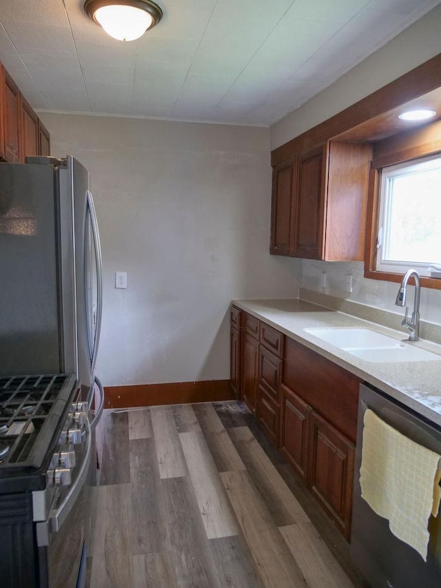 510 W Harrison St, Villa Grove, IL 61956 - kitchen with stainless steel appliances, a sink, light countertops, dark wood-style flooring, and brown cabinetry